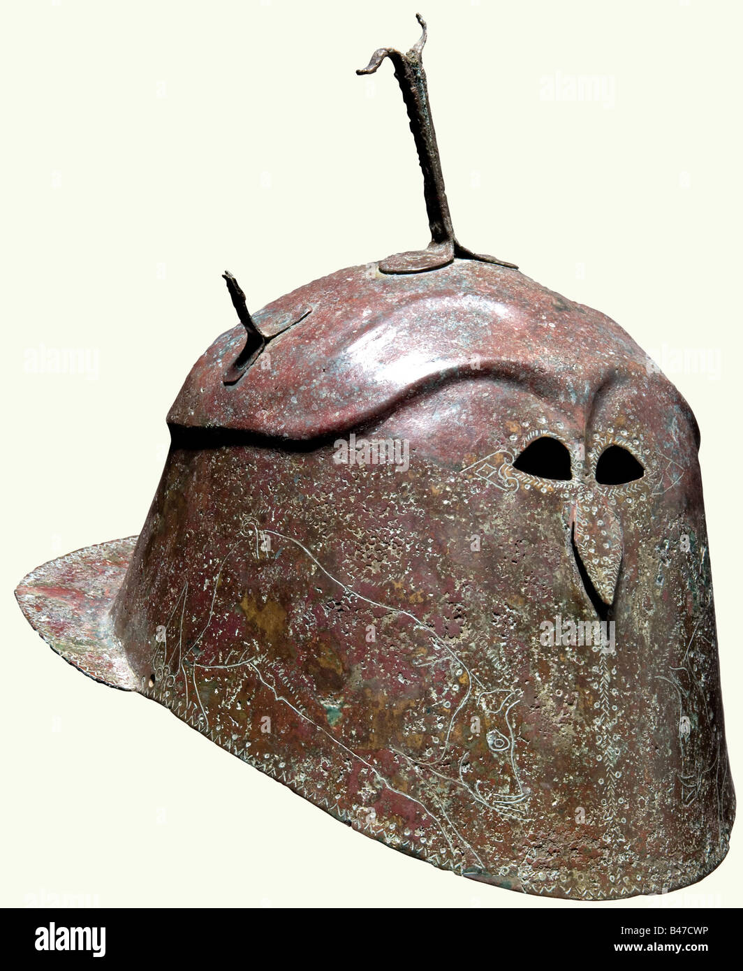 Un casque en bronze de type Apulian-Corinthian, dans le sud de l'Italie, la première moitié du 5ème siècle avant J.-C. Forgé en un morceau de bronze de feuille, la moitié supérieure séparée et fait légèrement plus large que les côtés par une crête extrudée. En haut, une fourche en bronze et les restes de deux supports latéraux, le front avec deux rangées de crêtes très hautes voûtées fixées sur des fentes d'yeux extrêmement petites en forme d'amande au-dessous desquelles un petit et légèrement proéminent 'nez'. Les joues gravées d'un grand et très gracieux, bien dessiné boar de chaque côté, les environs des yeux, du nez et de l'hel, Banque D'Images
