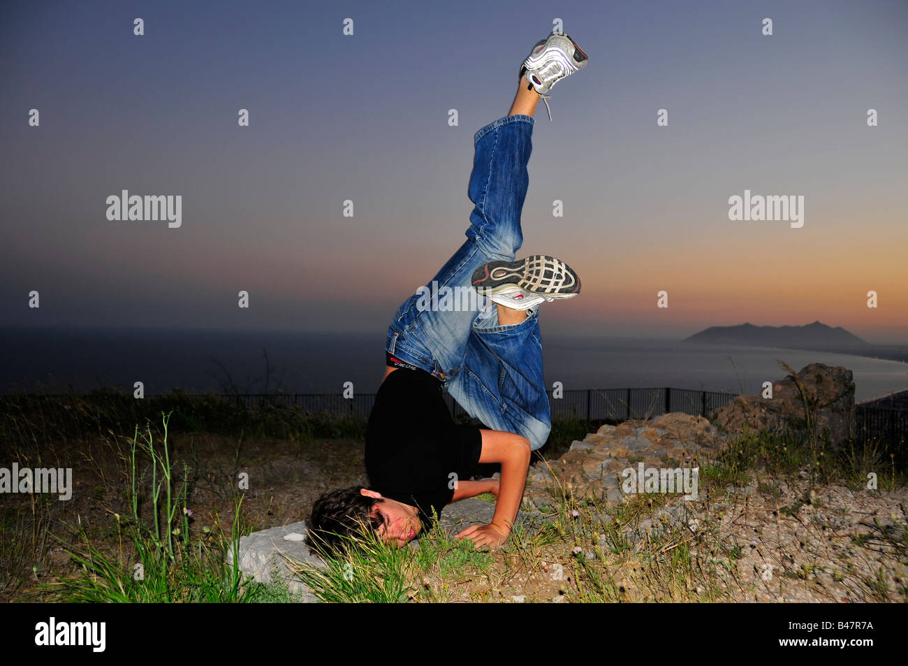 Le break dance au coucher du soleil contre la mer Banque D'Images