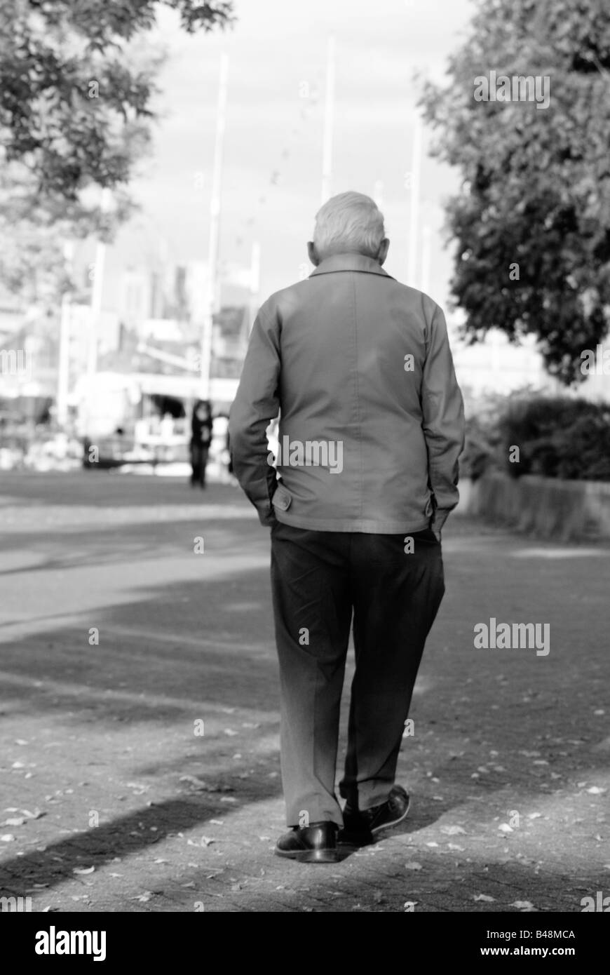Photo monochrome d'un vieil homme shuffling loin dans la distance Banque D'Images