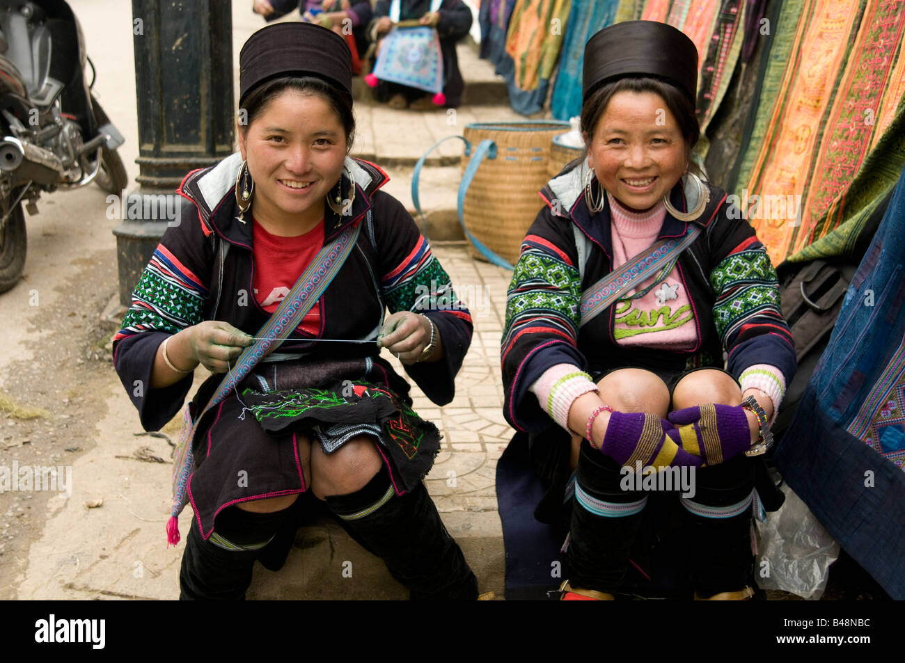 Deux femmes souriantes et heureuses de Hmong qui font des vêtements ethniques dans les rues de Sapa Vietnam Banque D'Images