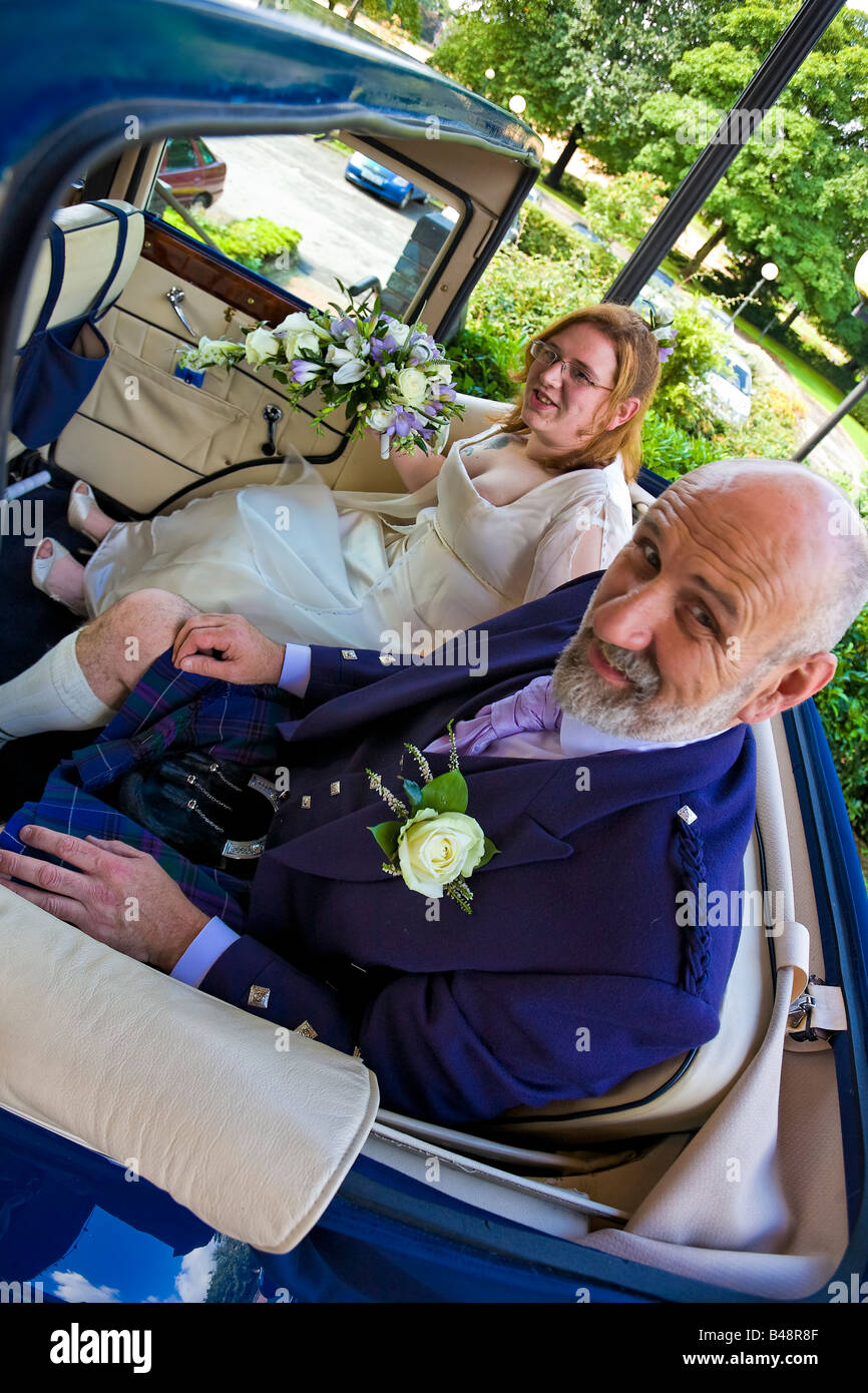 Mariée et le père de la Mariée arrivent en voiture à toit ouvert au mariage traditionnel écossais Banque D'Images