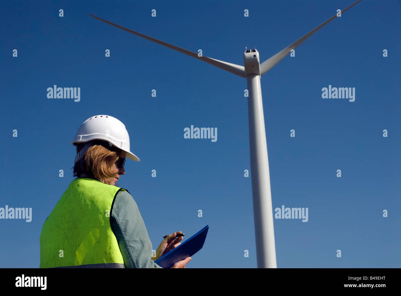 Ingénieur emplois de col vert femelle à côté de la turbine éolienne wind farm Banque D'Images