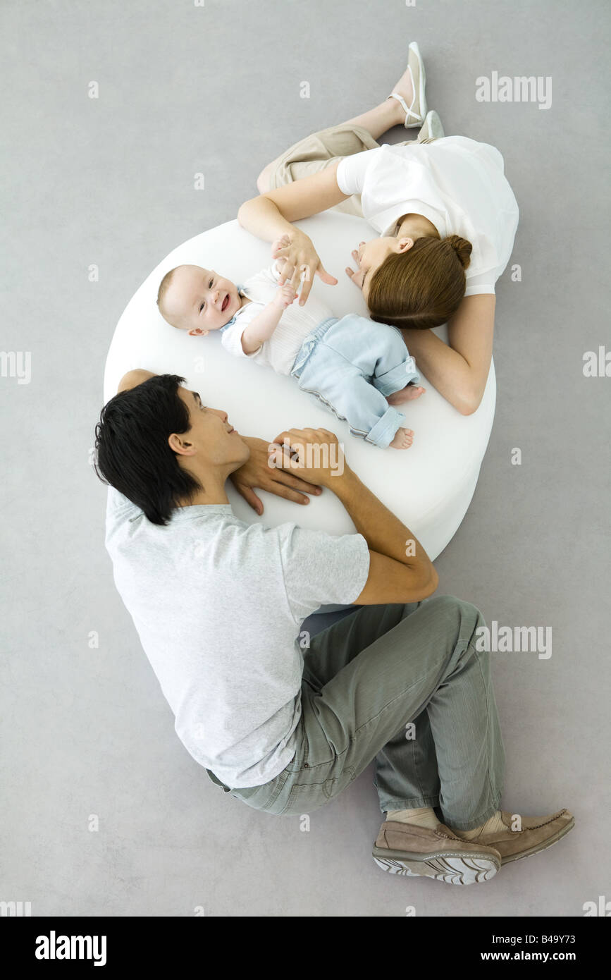 Les parents et le bébé se détendre sur un pouf, baby holding mother's hand, overhead view Banque D'Images