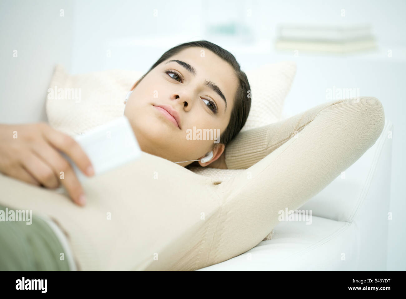 Jeune femme couchée sur le dos, listening to MP3 player Banque D'Images