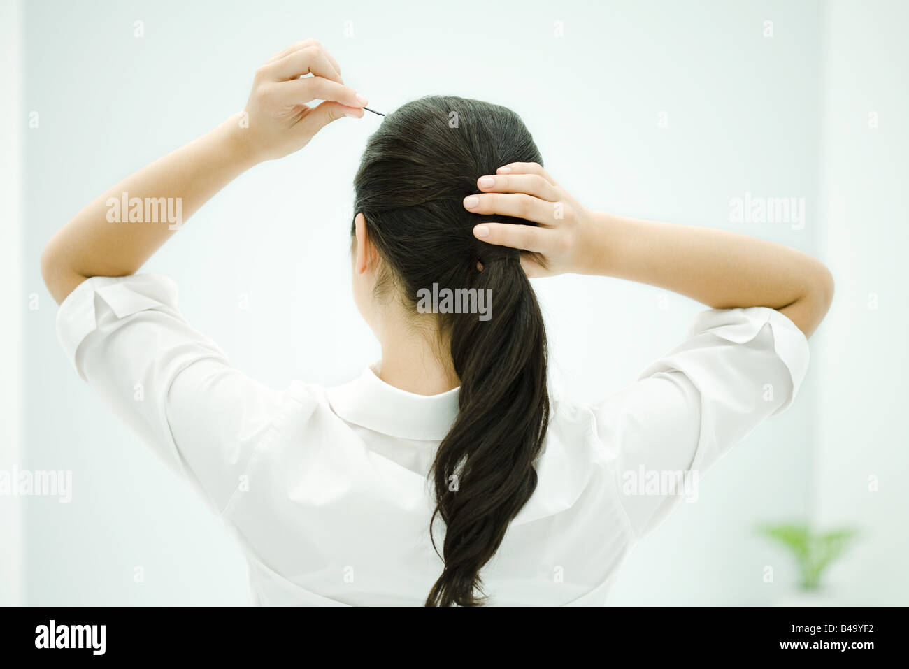 La mise en queue de cheveux Femme, bras levés, vue arrière Banque D'Images