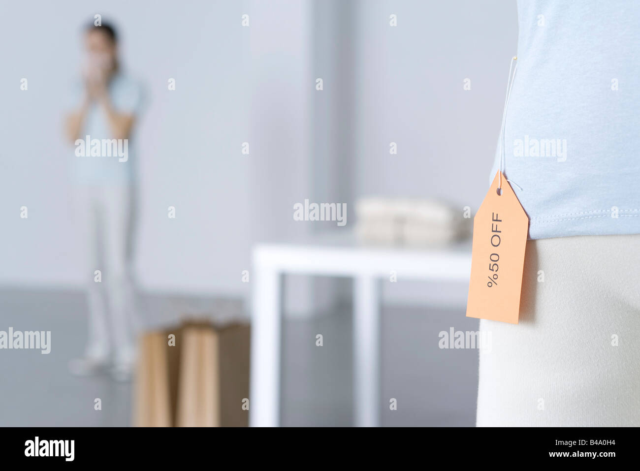 Close-up de vente tag sur shirt, femme debout en arrière-plan Banque D'Images