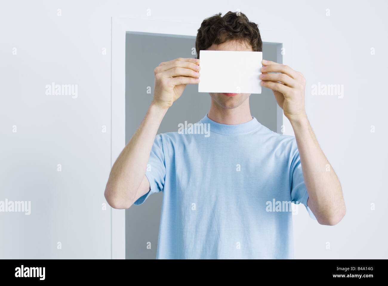 Young man holding blank card index en face de visage Banque D'Images