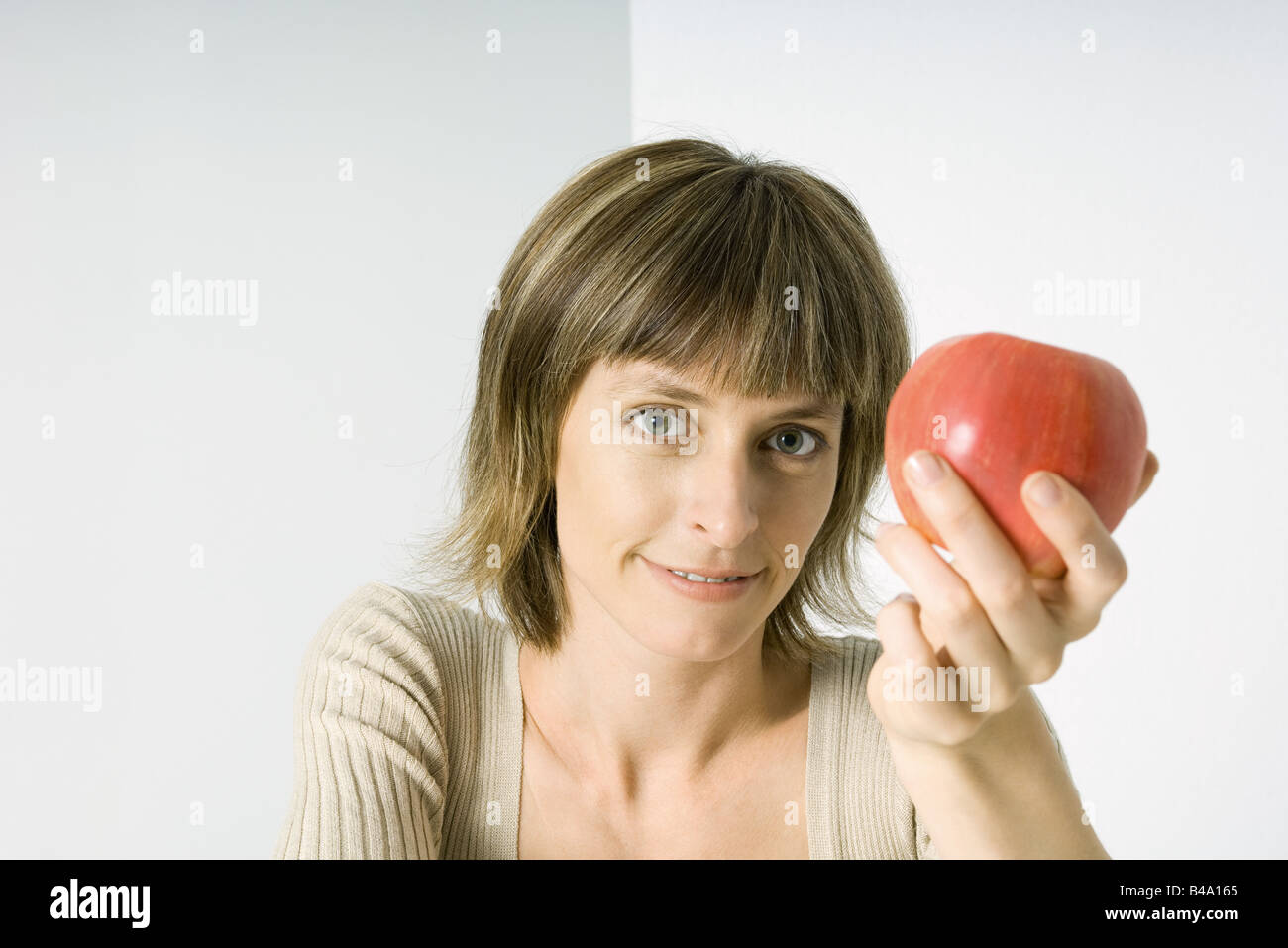 Woman holding red apple, smiling at camera Banque D'Images