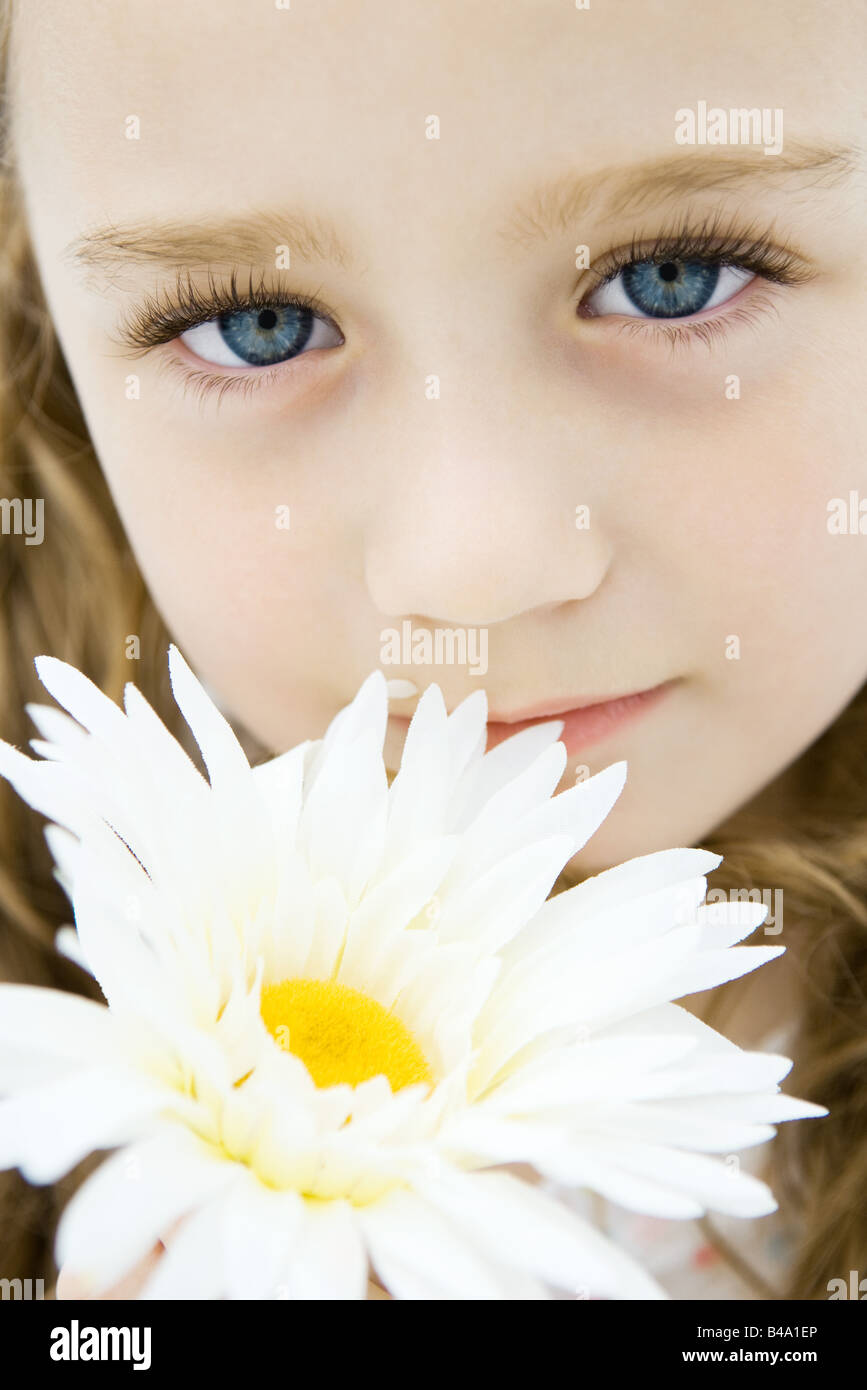 Petite fille aux yeux bleus holding daisy, portrait, close-up Banque D'Images