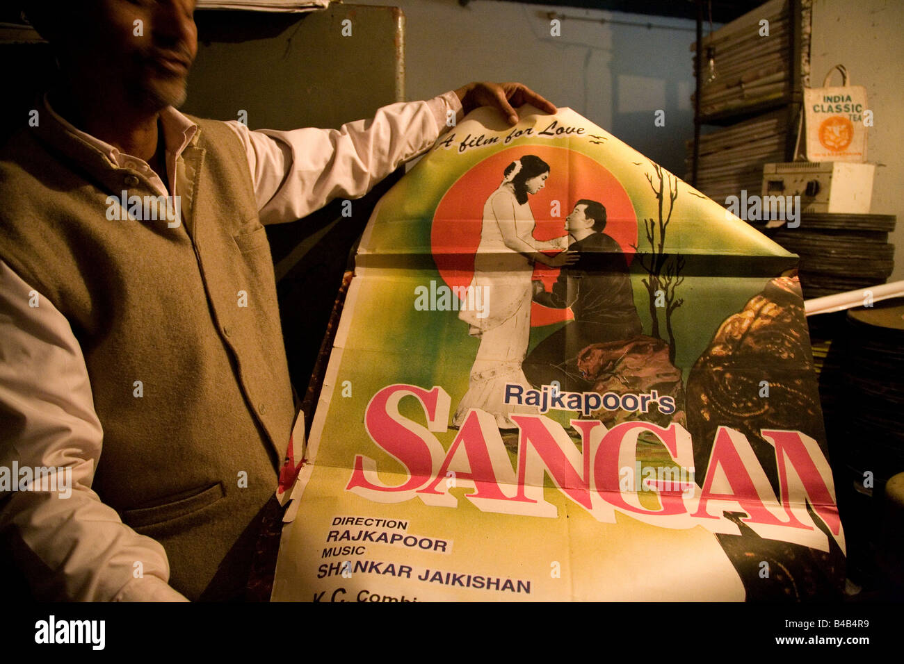 Un homme tient le coup une affiche publicitaire d'un film dans un film Rajkapoor distributeurs à Varanasi, Inde. Banque D'Images