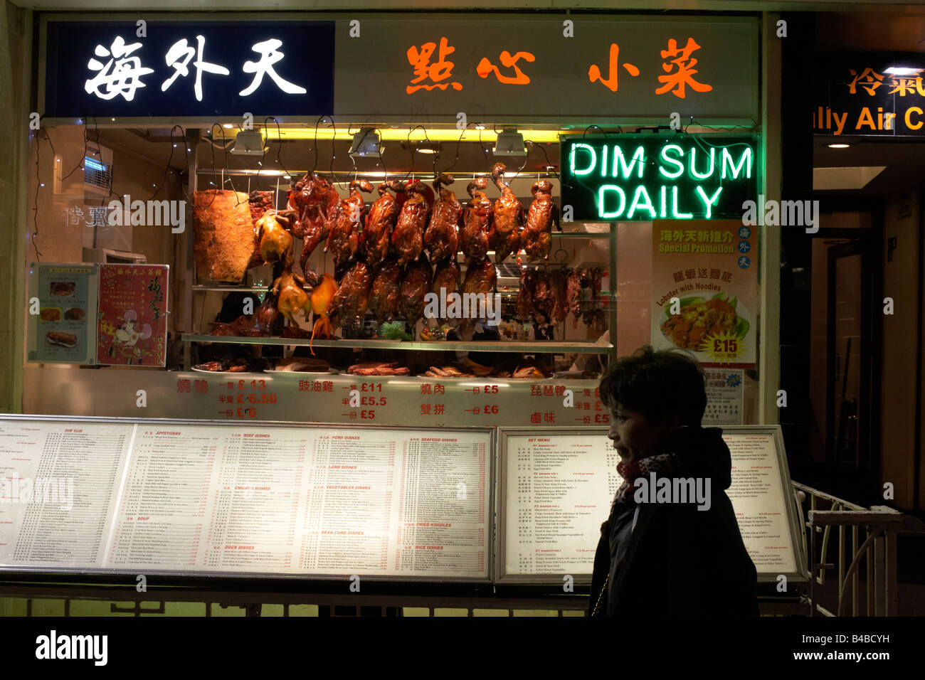 Un passant se trouve à l'extérieur d'un restaurant chinois proposant des Dim Sum dans le quartier chinois de Londres accueil communauté ethnique chinoise. Banque D'Images