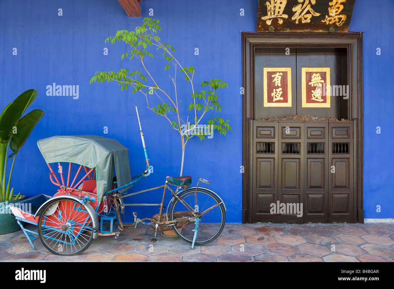 Asie, Malaisie, Penang, Pulau Pinang, Georgetown, quartier chinois, détail d'un Trishaw rouge et porte en chinois traditionnel Banque D'Images