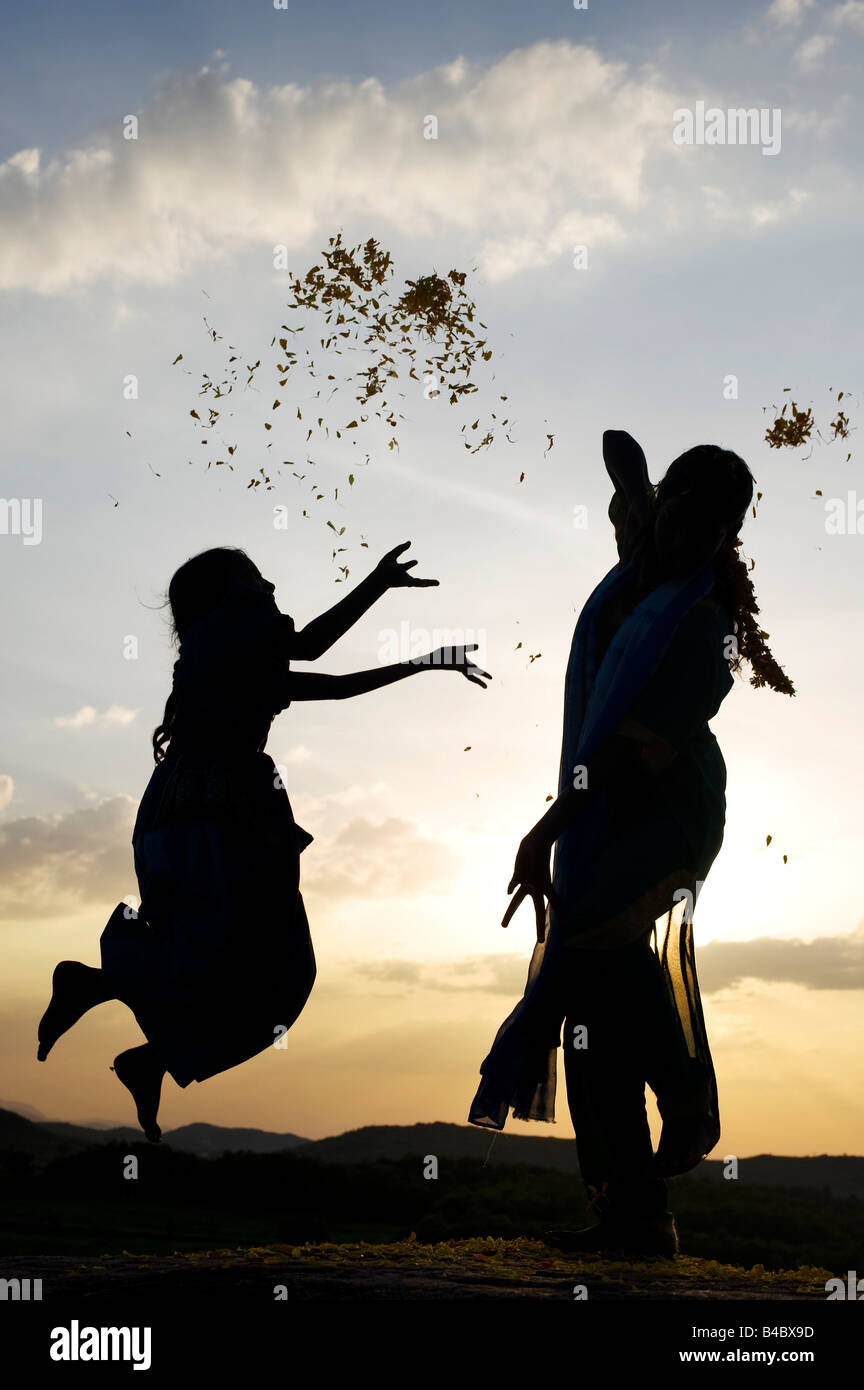 Deux sœurs indiennes effectuant une danse dévotionnelle hindoue sur un rocher silhouette au coucher du soleil. L'Andhra Pradesh, Inde Banque D'Images