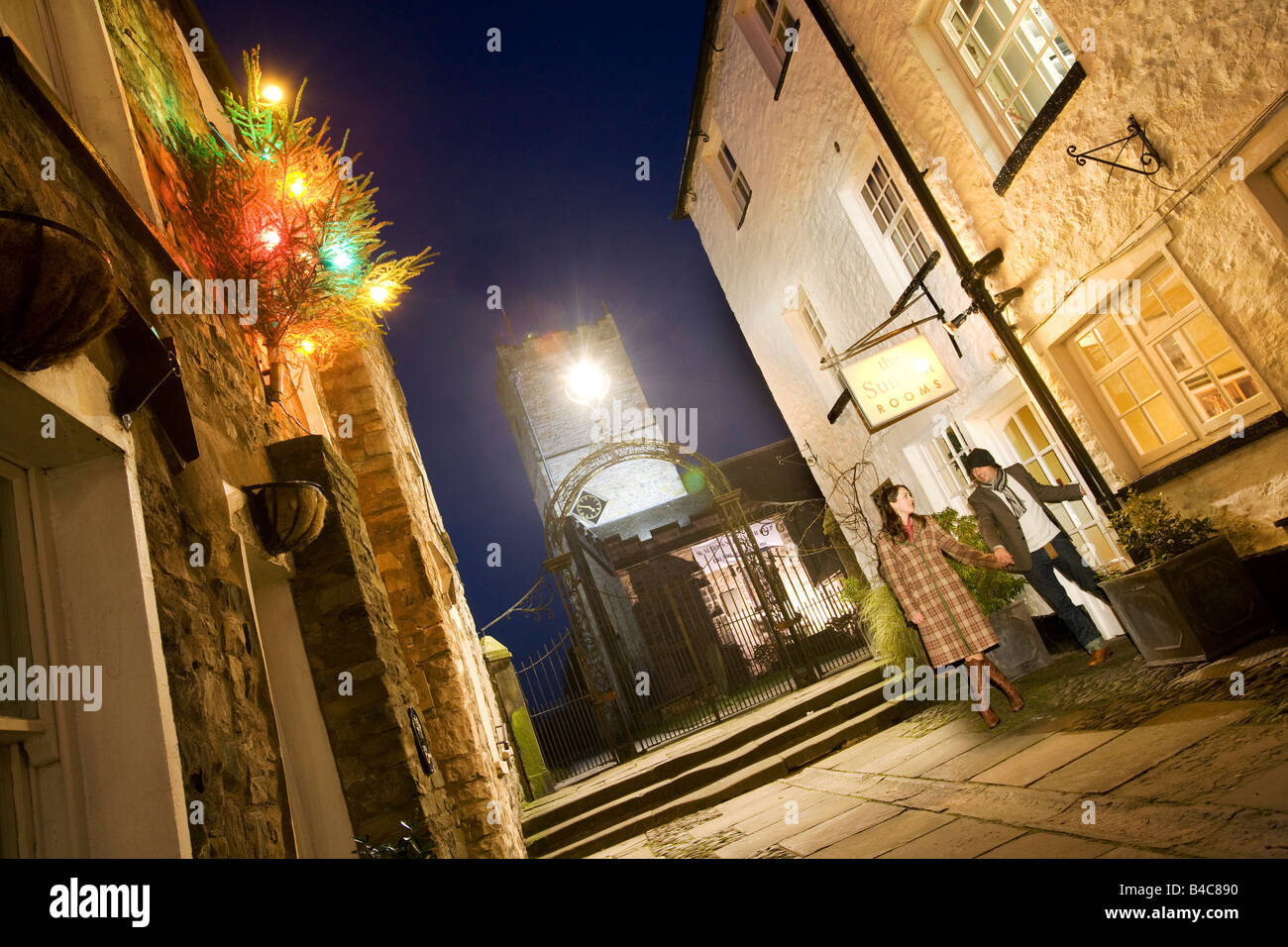 Couple laissant un pub traditionnel, l'auberge de soleil avec des décorations de Noël dans une rue de Kirkby Lonsdale, Cumbria Banque D'Images