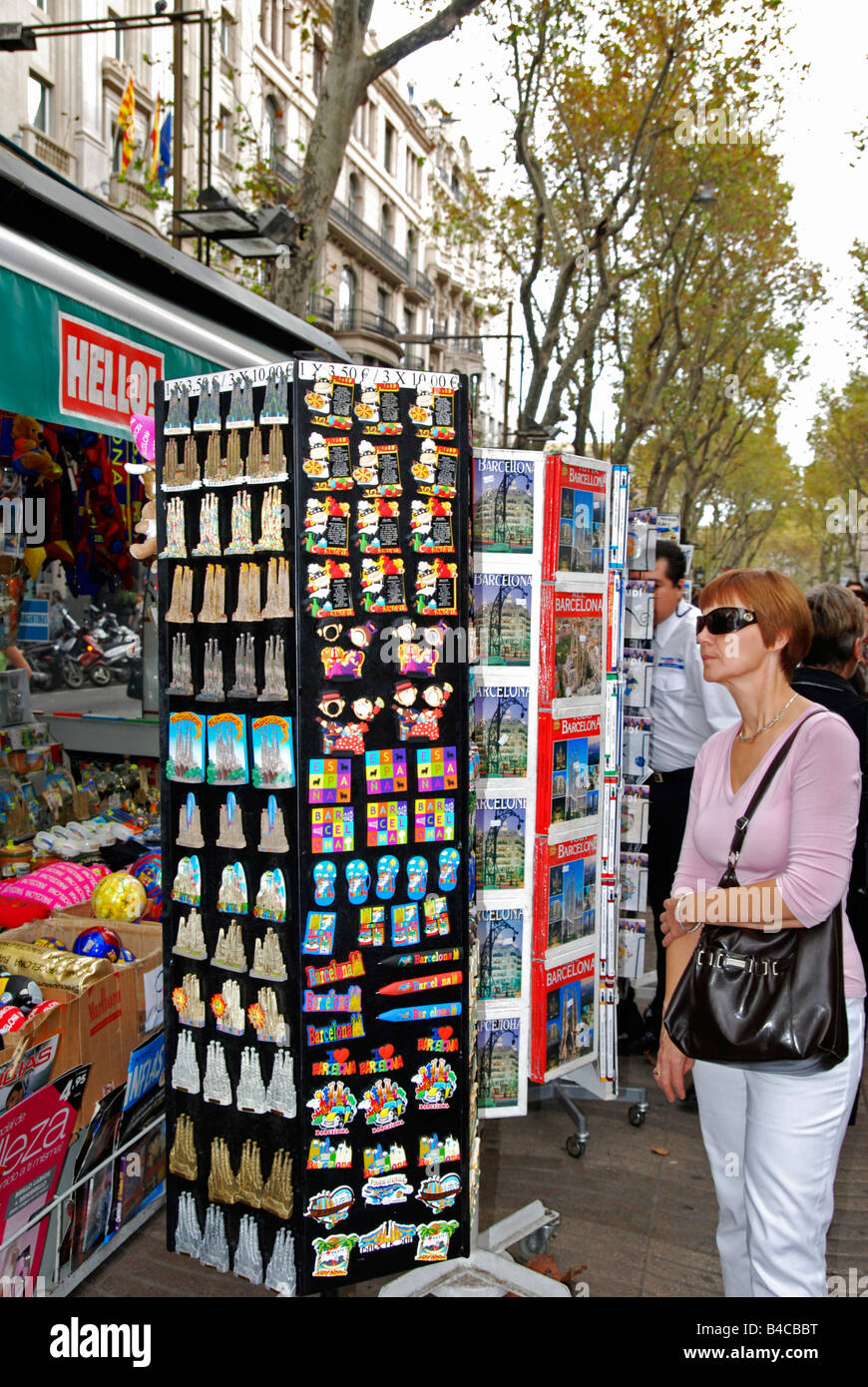 Les touristes à la recherche d'une femelle à souvenirs sur un étal sur la rambla, Barcelone, Espagne Banque D'Images