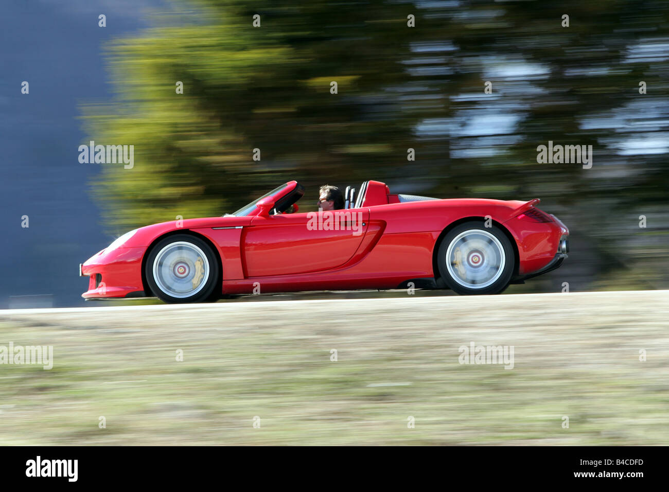 Voiture, PORSCHE CARRERA GT, modèle de l'année 2005-, rouge, convertible, open top, conduite, side view, country road, photographe : Hans Diet Banque D'Images