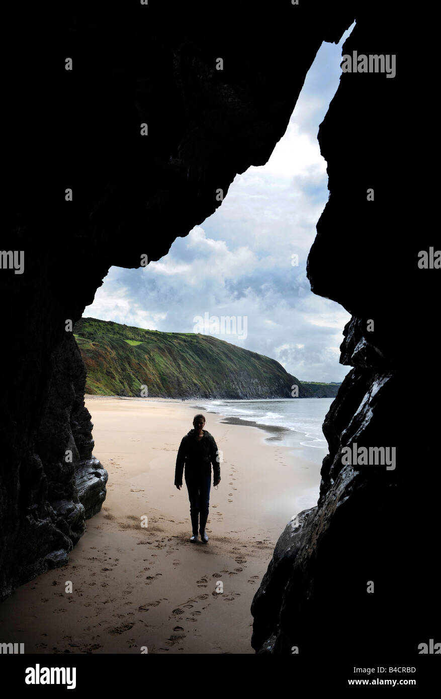 Une FIGURE ENTRE DANS UNE GROTTE SUR LA PLAGE À PENBRYN CEREDIGION WEST WALES UK Banque D'Images