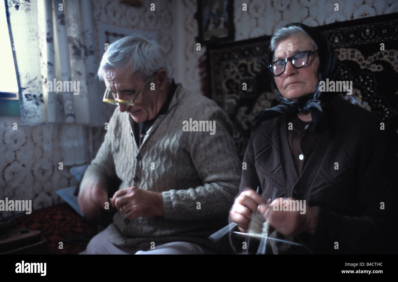 Une femme tricote des chaussettes assis sur le lit dans sa maison de deux pièces avec son mari la Transylvanie Roumanie Banque D'Images