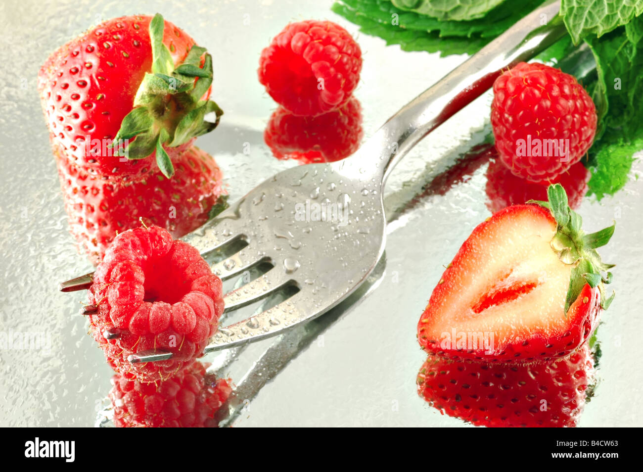 Réfrigérées fraîches framboises et fraises à la menthe sur un fond réfléchissant avec une faible profondeur de champ Banque D'Images