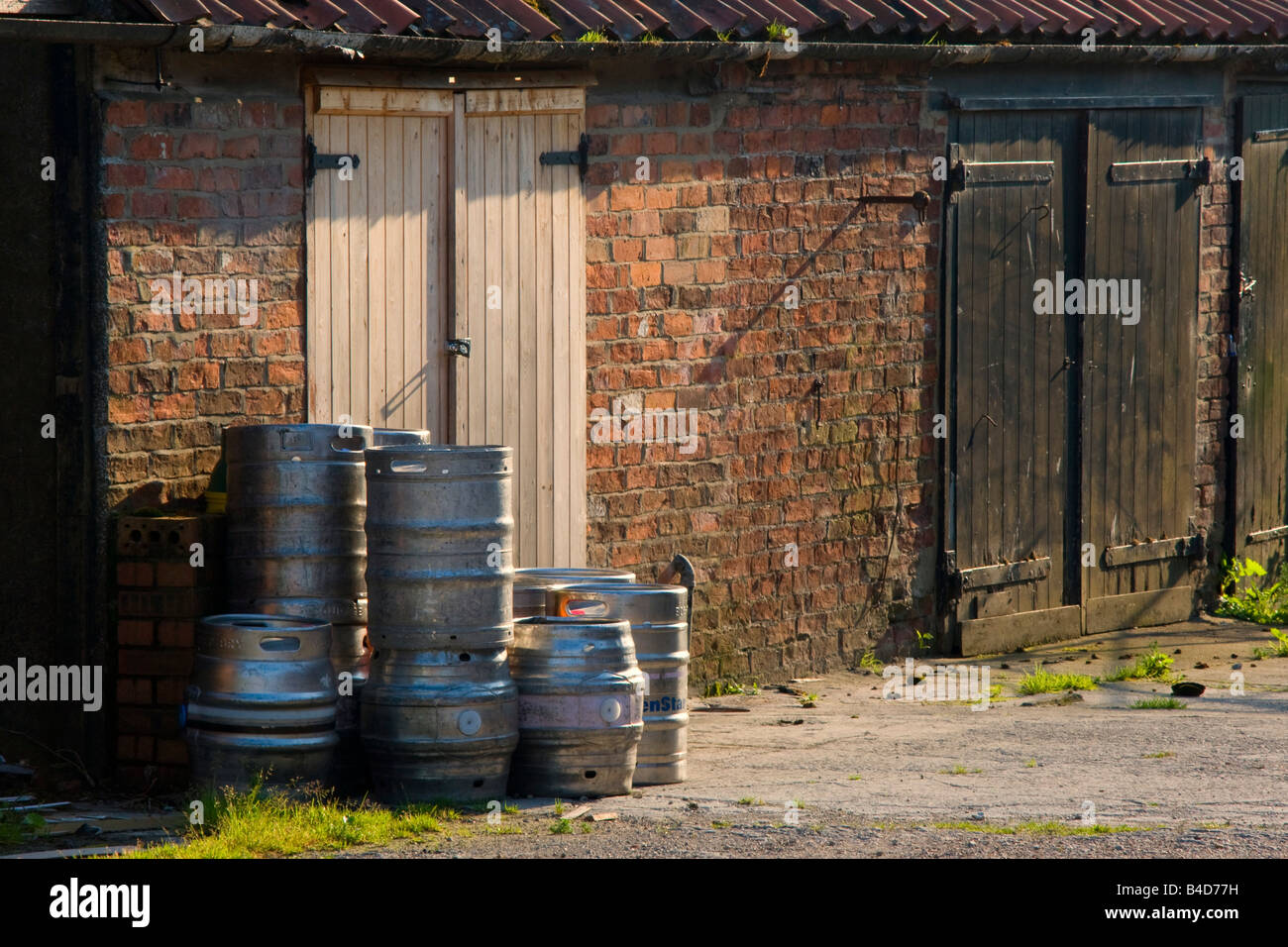 Barils entassés en face de portes de grange Banque D'Images