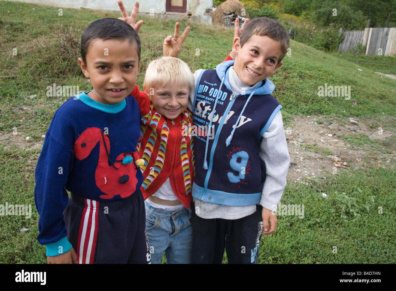 La Transylvanie Roumanie Europe Septembre Trois chauds deux garçons du village roumain avec les cheveux sombres encadrant un garçon blond donnant V sign Banque D'Images