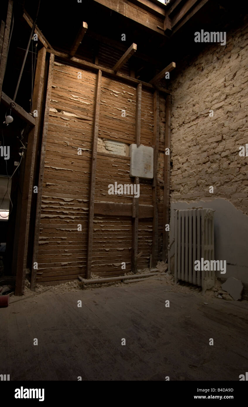 Des poutres apparentes et briques structurelles d'un radiateur dans le coin d'une maison en rangée partiellement démoli. Banque D'Images