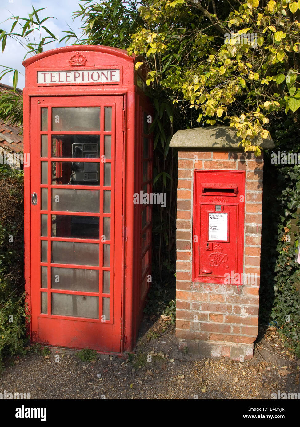 Une boîte de téléphone rouge vif et une boîte postale dans un pilier en brique sur St James Street UK Suffolk Dunwich Banque D'Images
