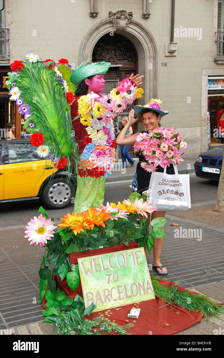 Une statue de l'artiste de rue sur la Rambla de Barcelone, mettre des fleurs sur une femelle touristes hat. Banque D'Images