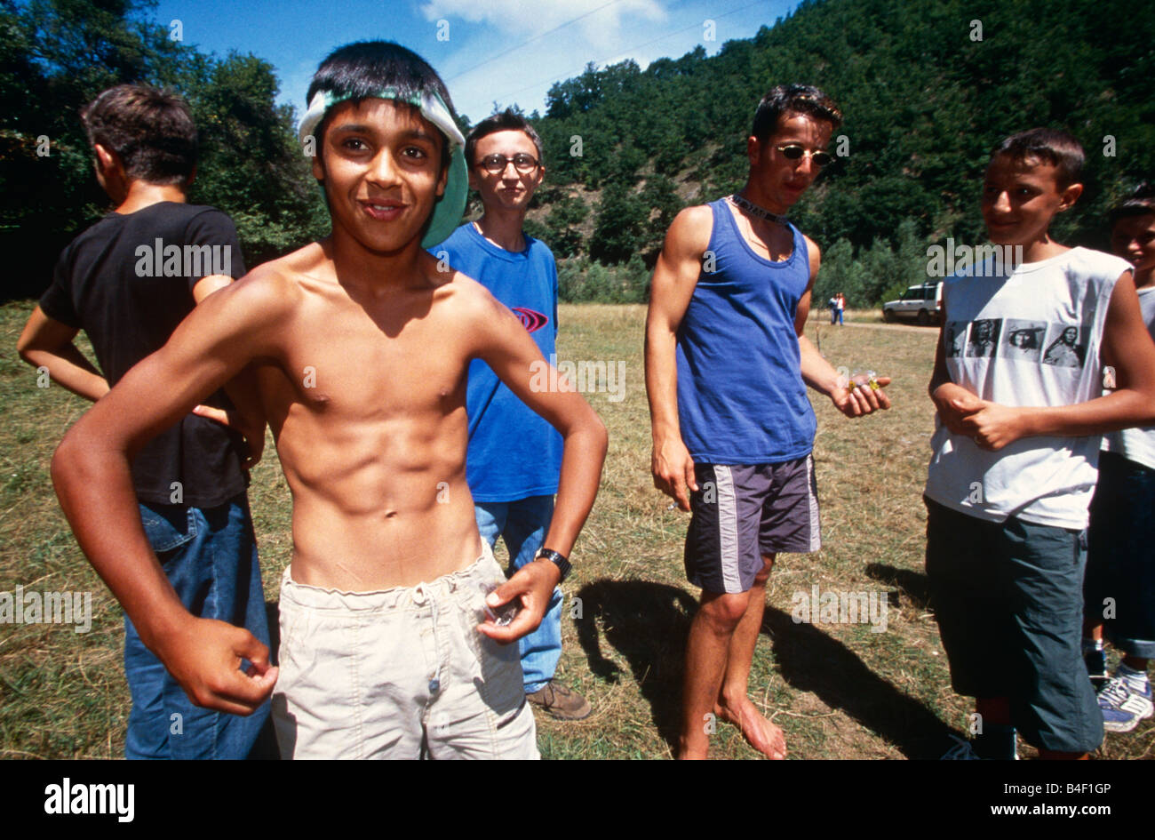 Boy showing off muscles, les amis en arrière-plan, le Kosovo, l'Albanie Banque D'Images