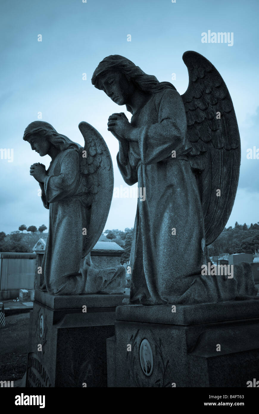 Deux anges priant reste au-dessus de pierres tombales anciennes au Christ notre Rédempteur Cemeter Catholique, Pittsburgh, Pennsylvanie. Banque D'Images