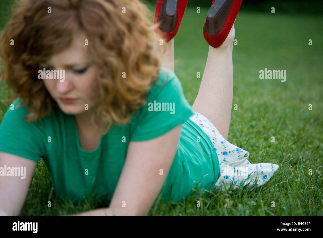 Une jeune femme allongée sur l'herbe sur son front, appuyée sur ses coudes Banque D'Images
