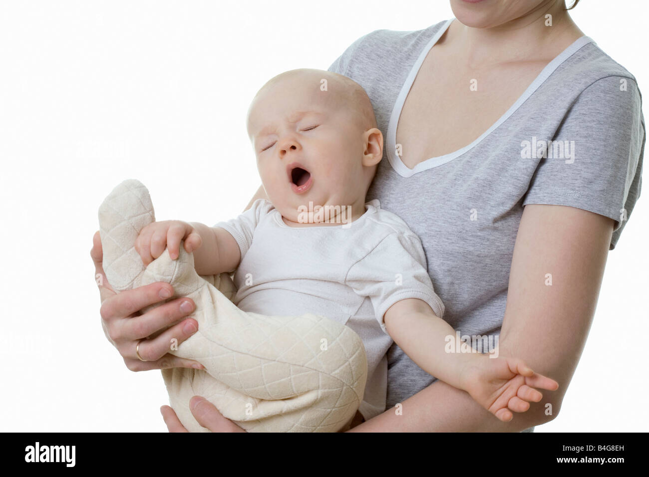 Un bébé assis dans les bras d'une femme et le bâillement Banque D'Images