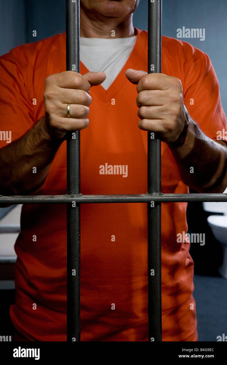 Un prisonnier debout derrière la porte de sa cellule de prison Banque D'Images