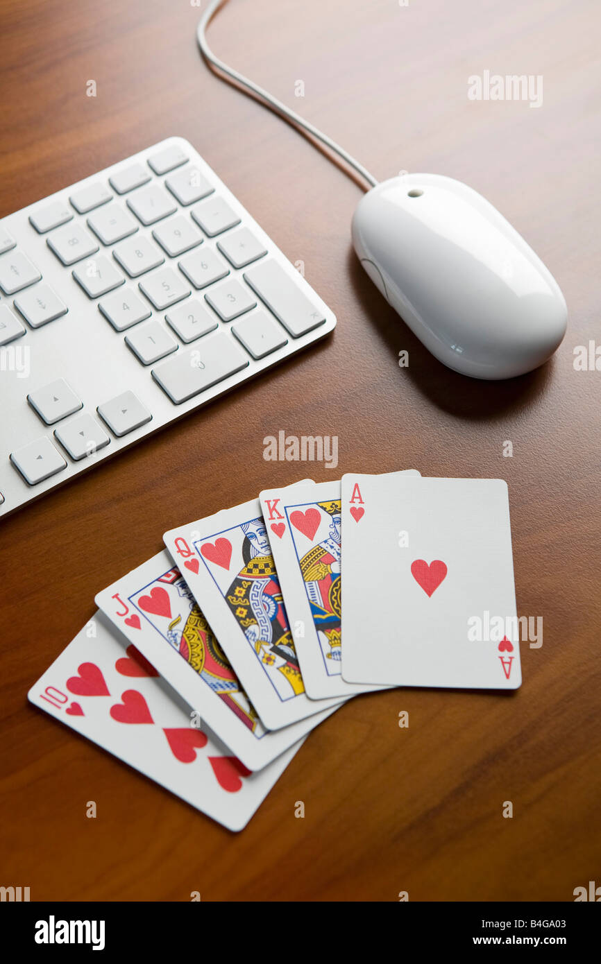 Une main de poker royal flush sur une table à côté d'un clavier et souris d'ordinateur Banque D'Images