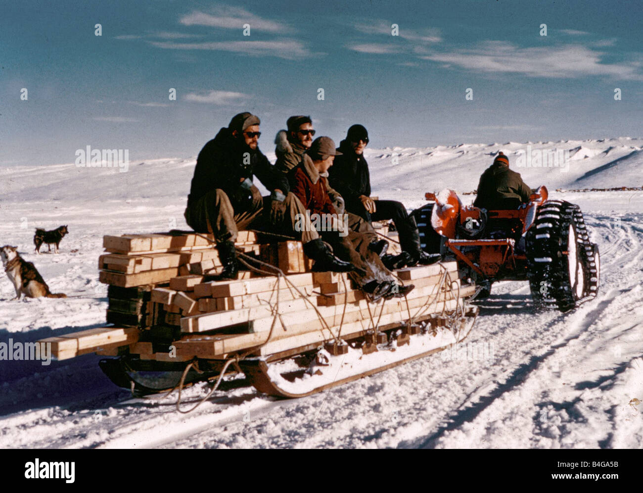 L'expédition Antarctique 1956 Trans 1958 Membres de l'équipe d'expédition s'asseoir sur le dessus d'un traîneau chargé de bois comme un tracteur tire sur eux à travers la neige répondre explorateurs au Pôle Sud membres de l'équipe de tenter la première traversée en surface de l'Antarctique se sont regroupés au Pôle Sud Le Néo-zélandais Sir Edmund Hillary qui a déjà conquis l'Everest est arrivé avec son équipe il y a 17 jours tôt cet après-midi, Sir Edmund s'est félicité de l'équipe britannique dirigée par le Dr Vivian Bunny Fuchs au Pôle Sud les équipes britannique et néo-zélandais sont membres d'une expédition Antarctique Trans du Commonwealth Banque D'Images