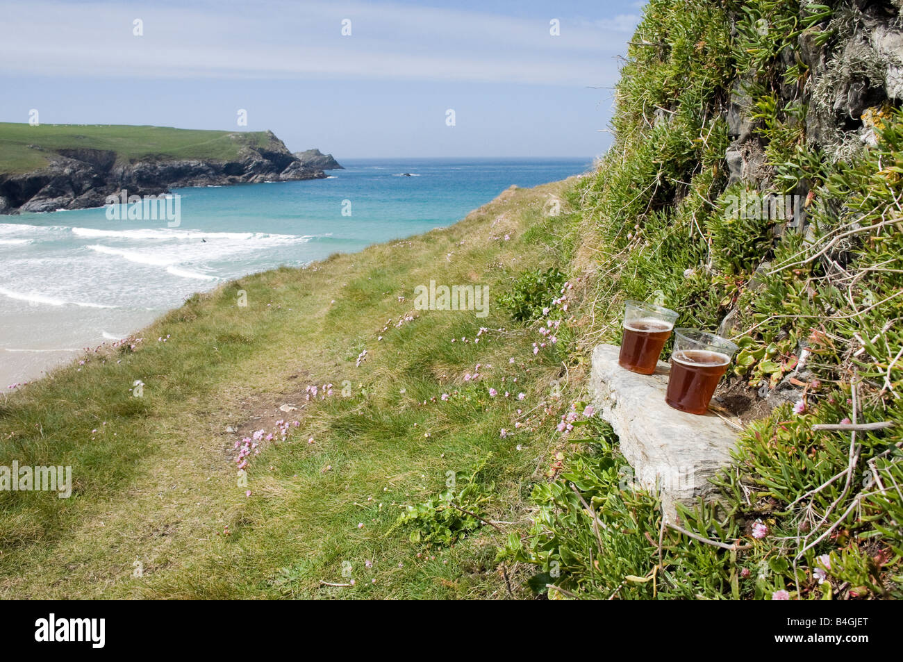 Deux pintes de bière s'asseoir sur un banc d'ardoise sur le sentier du littoral cornouaillais avec sky côte et mer en arrière-plan, UK Crantock Banque D'Images