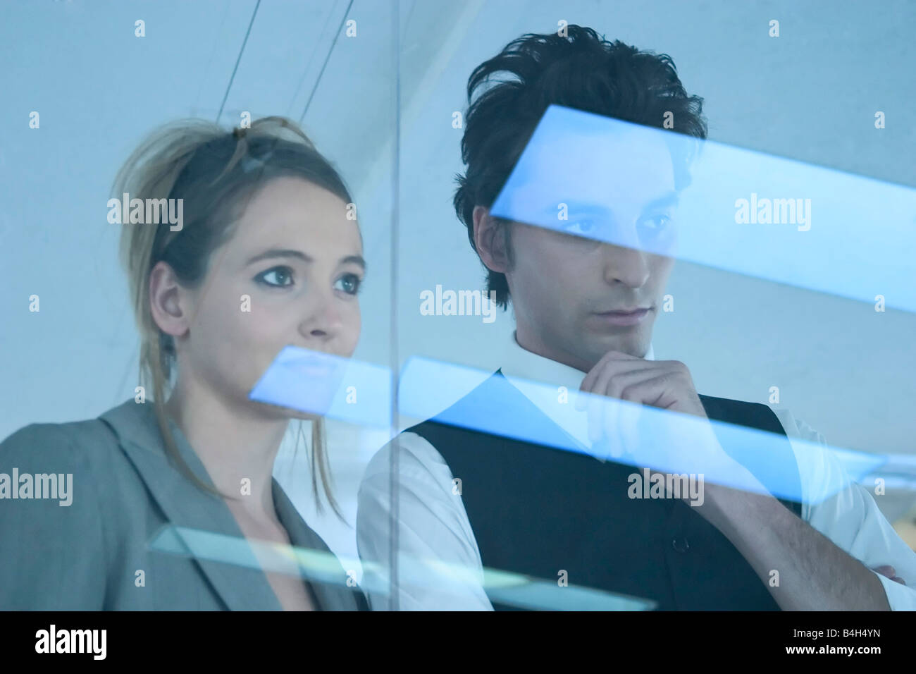 Businessman and businesswoman looking through window Banque D'Images