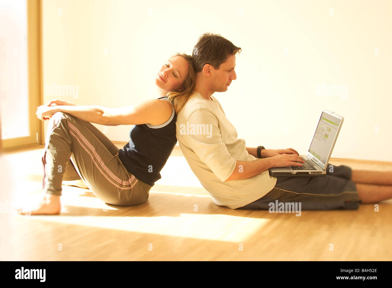 Portrait of young woman leaning against son mari working on laptop Banque D'Images