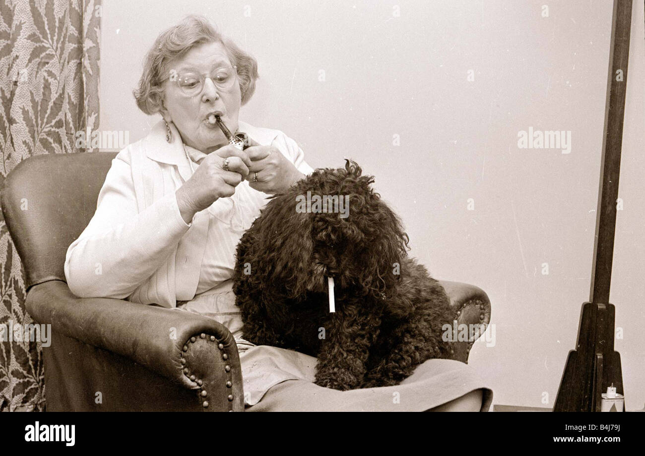 Le Caniche qui mange des cigarettes d'une vieille femme fumant une pipe avec son animal de compagnie caniche nain qui mange des cigarettes Banque D'Images