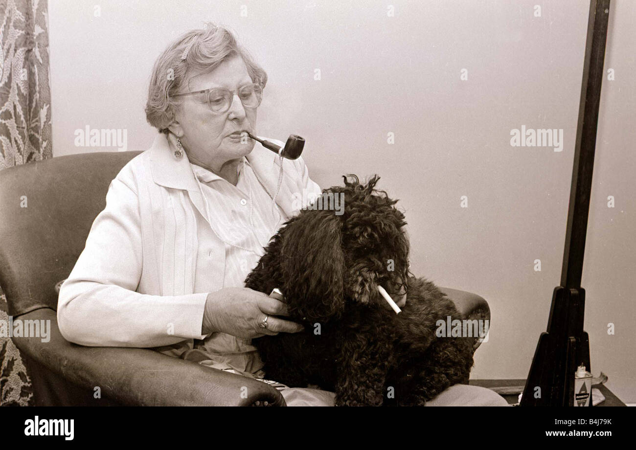 Le Caniche qui mange des cigarettes d'une vieille femme fumant une pipe avec son animal de compagnie caniche nain qui mange des cigarettes Banque D'Images