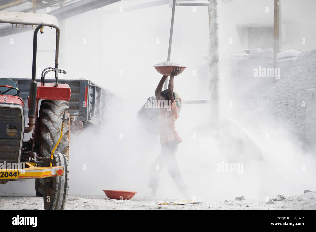 Les hommes indiens de mettre de la pierre concassée dans une remorque, entouré par la poussière, sans protection, à l'écrasement fonctionne. L'Andhra Pradesh. L'Inde Banque D'Images