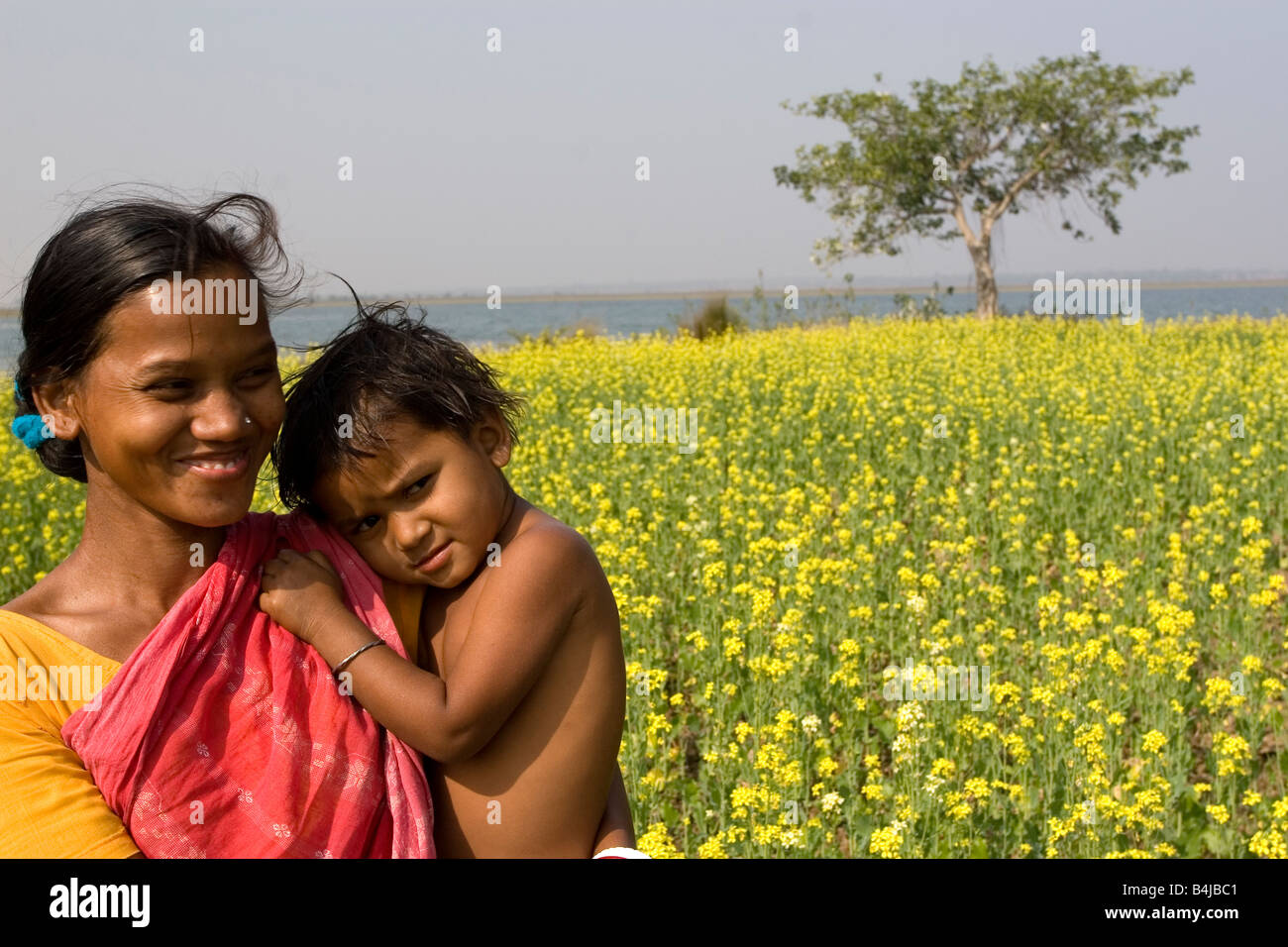 Villlage mothr avec son fils bénéficiant d''une salle de moment dans un champ de moutarde dans un village éloigné de Birbhum, Bengale occidental, Inde Banque D'Images