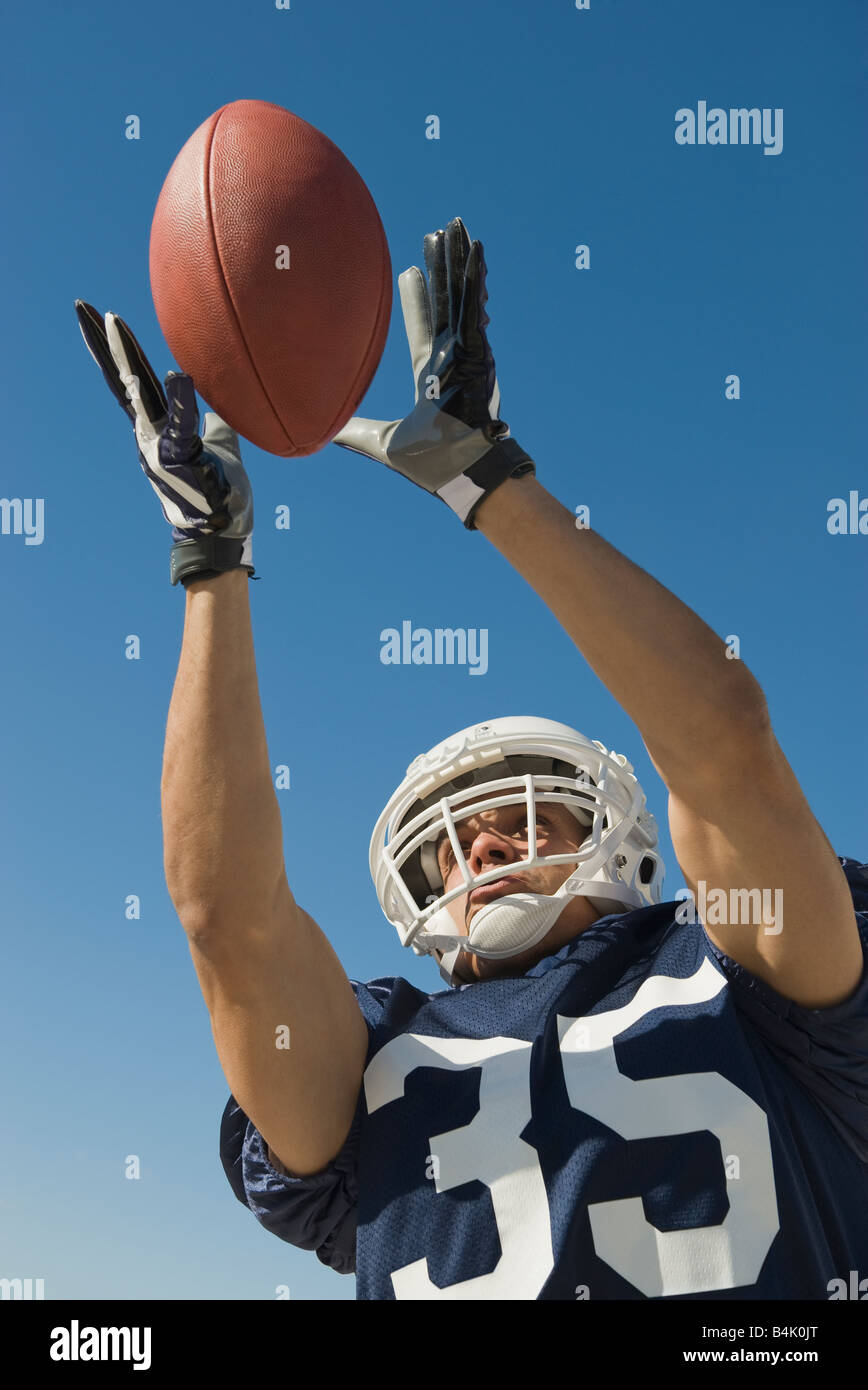 Hispanic male football player catching ball Banque D'Images