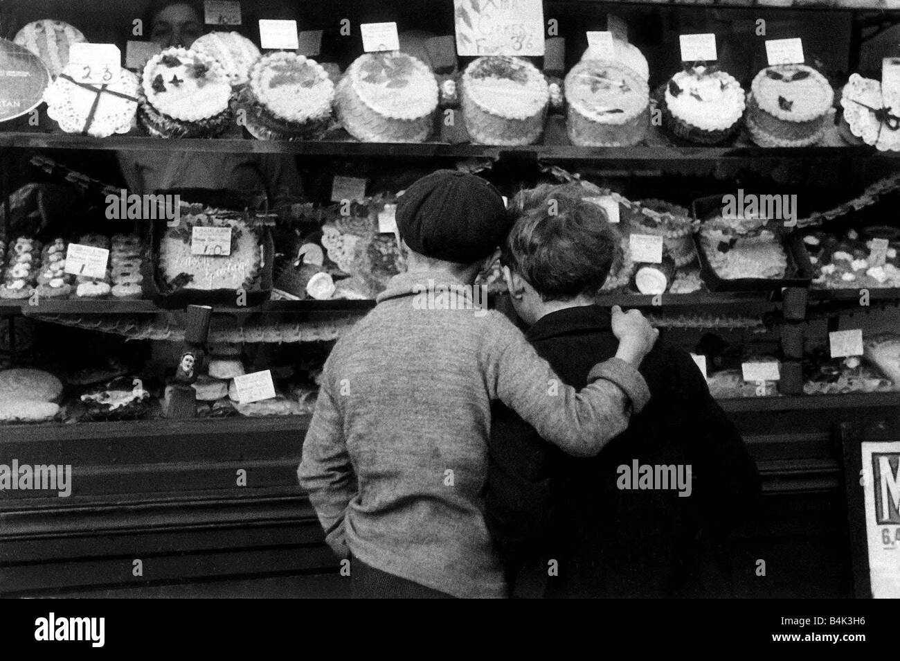Window Shopping Février 1935 enfants regarder dans une boulangerie locale fenêtre Légende friendshipimages Banque D'Images