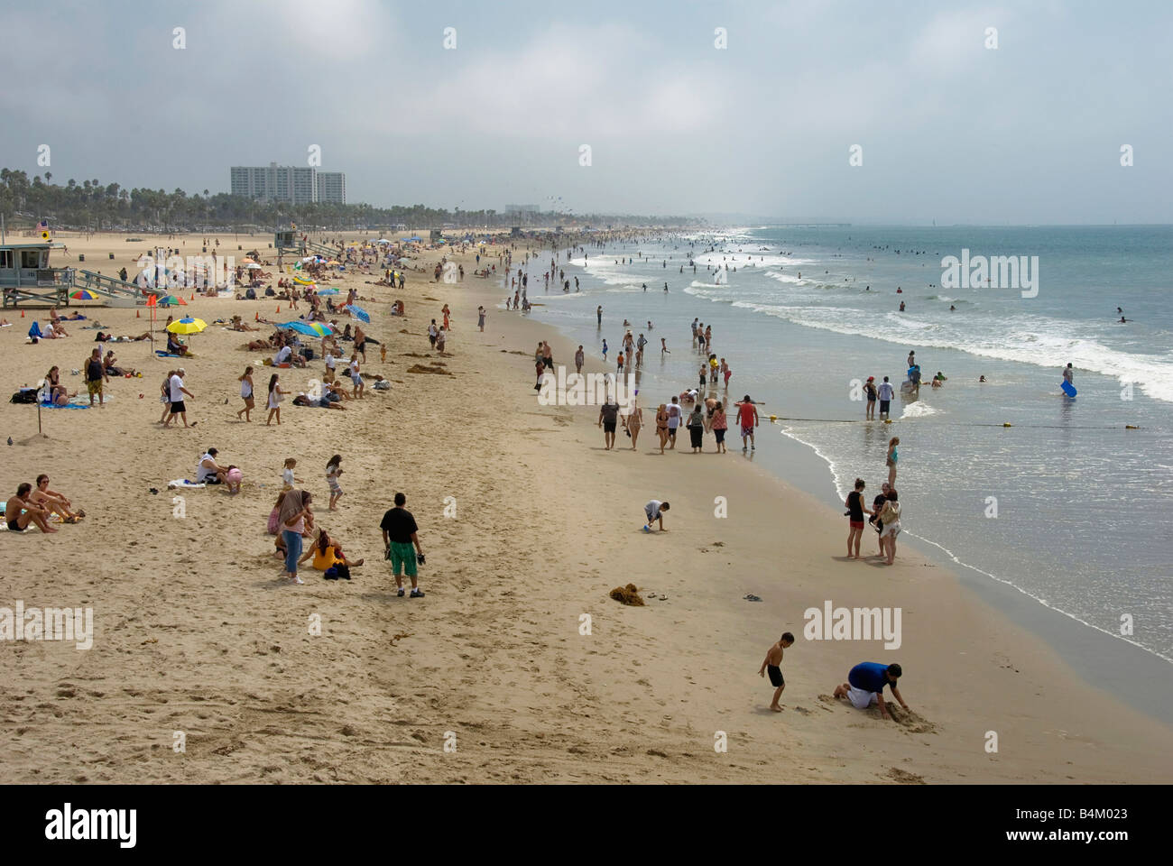 La plage de Santa Monica CA Personnes foule reposant, piscine, prendre le soleil et avoir l'amusement jouer des jeux, châteaux de sable, la marche, les vagues Banque D'Images