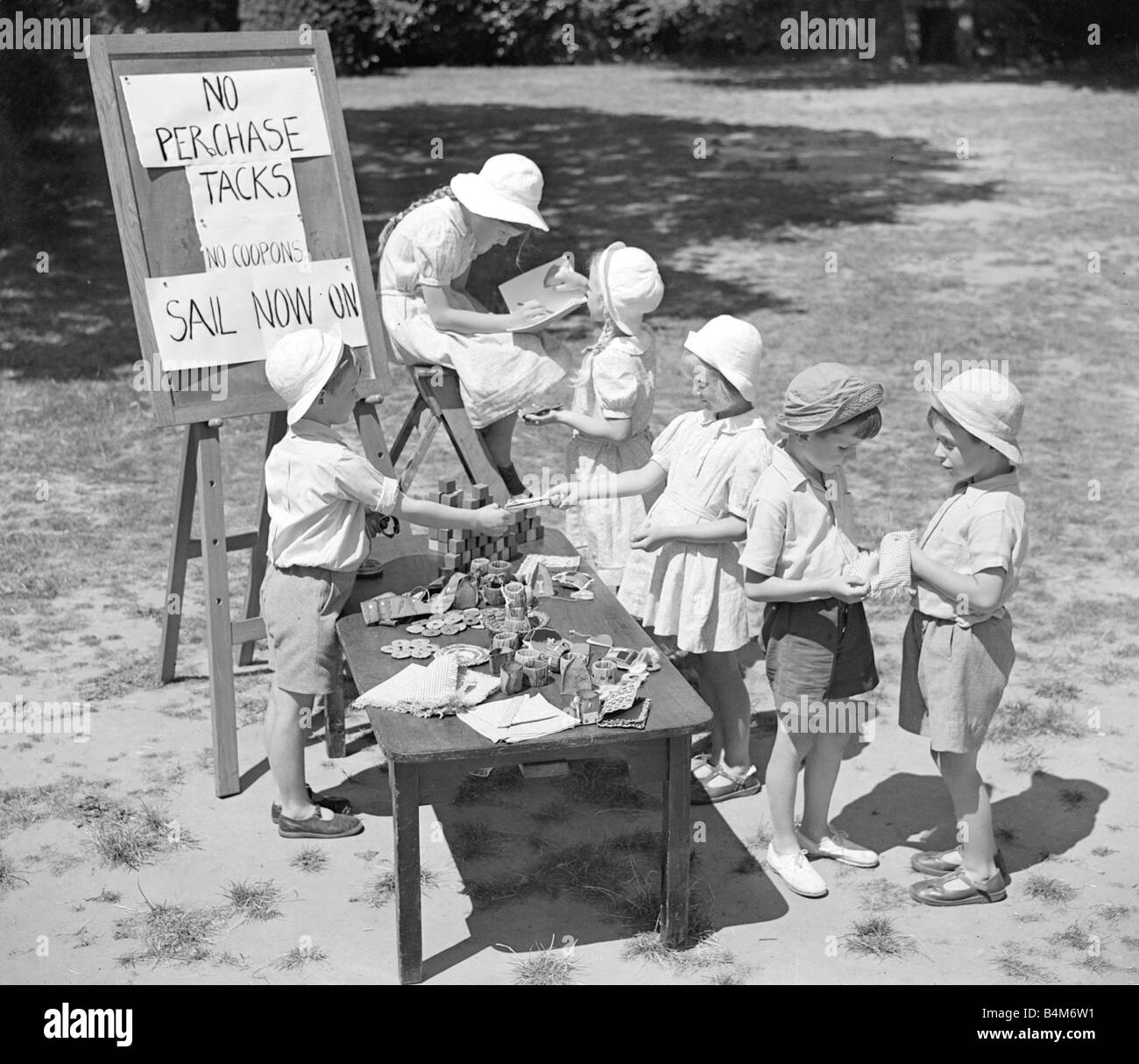 Enfants jouant boutiques au cours de l'été petit garçon debout derrière le tableau avec des marchandises organisé Sign reads No Perchase punaises aucun voile sur Coupons maintenant vers 1950 Banque D'Images