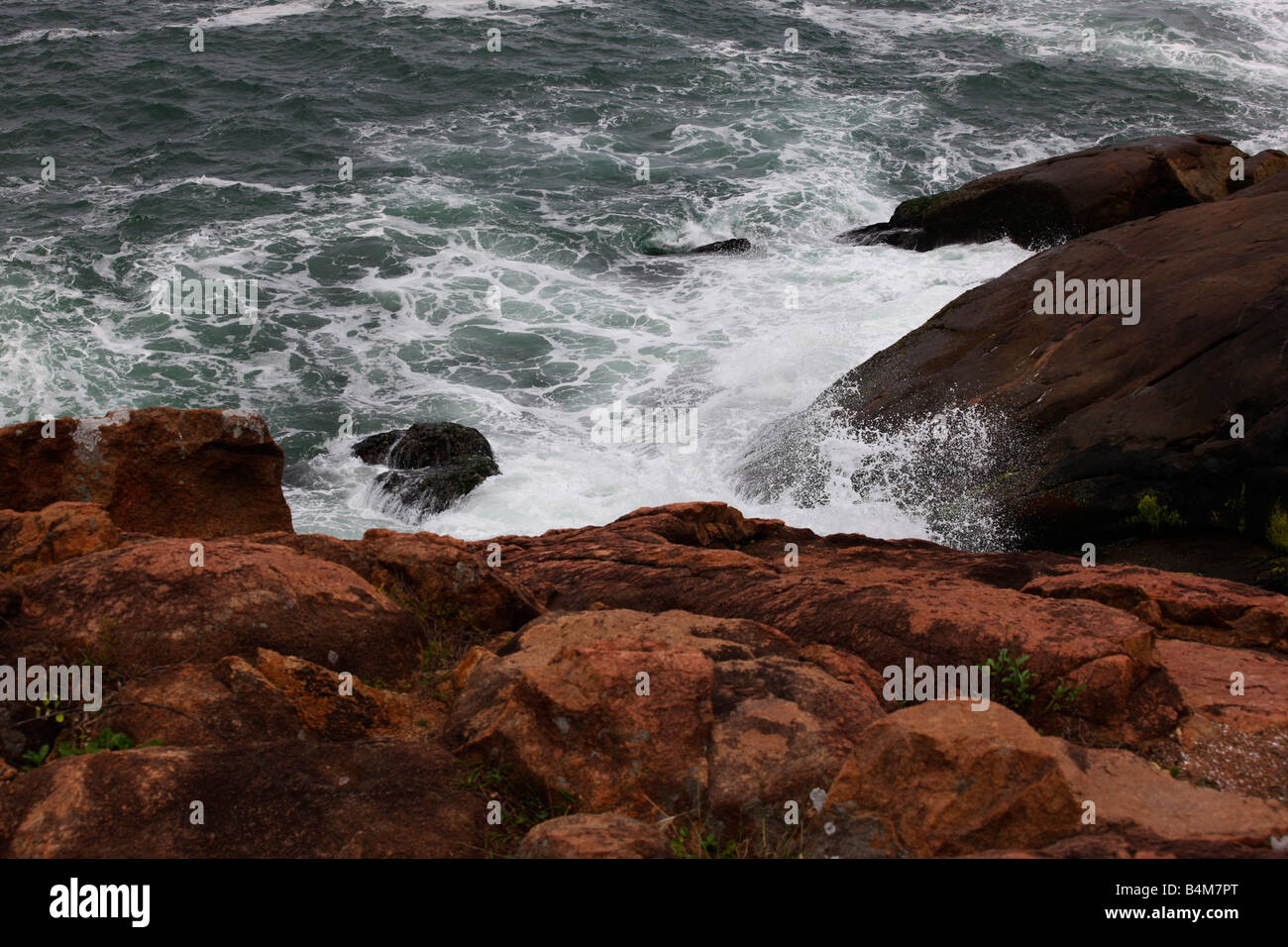 Vagues qui les roches rouges dans la zone côtière du Kerala, Inde Banque D'Images