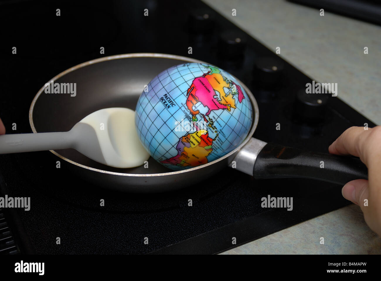 Un globe est montré être frit dans une poêle, sur un brûleur cuisinière représentant le concept de réchauffement global Banque D'Images