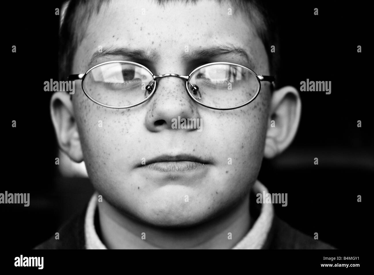 Close up portrait noir et blanc d'un jeune garçon portant des lunettes Banque D'Images