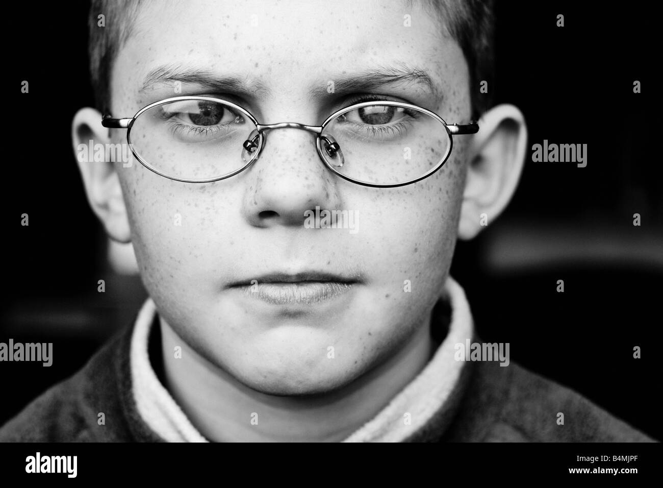 Close up portrait noir et blanc d'un jeune garçon portant des lunettes Banque D'Images